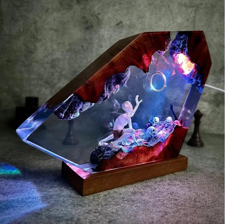 Studio view of gaunt figure reaching toward a ring in ember-lit resin on its display base with controlled illumination